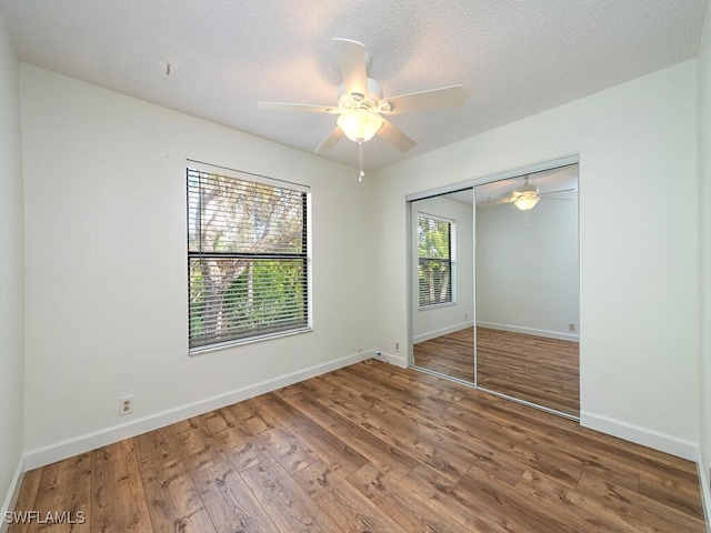 unfurnished bedroom with hardwood / wood-style floors, a textured ceiling, a closet, and ceiling fan