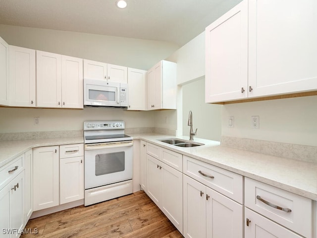 kitchen featuring white appliances, sink, light hardwood / wood-style flooring, white cabinetry, and lofted ceiling