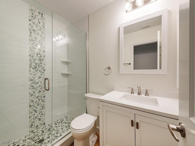 bathroom featuring a shower with door, vanity, and toilet