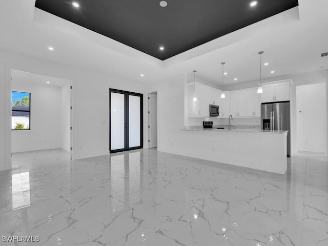 unfurnished living room with french doors, a tray ceiling, and sink