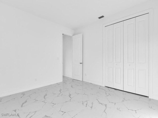 unfurnished bedroom with visible vents, baseboards, marble finish floor, and a closet