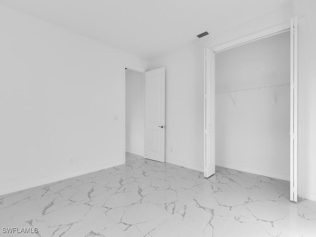 unfurnished bedroom featuring a closet, visible vents, marble finish floor, and baseboards