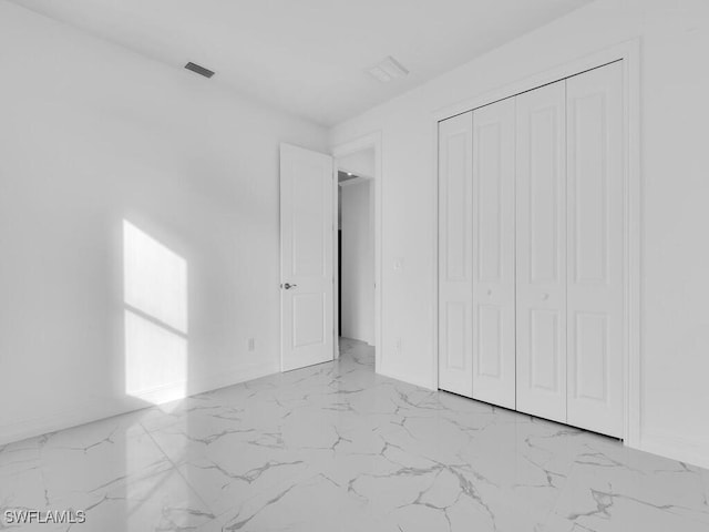 unfurnished bedroom featuring visible vents, baseboards, marble finish floor, and a closet