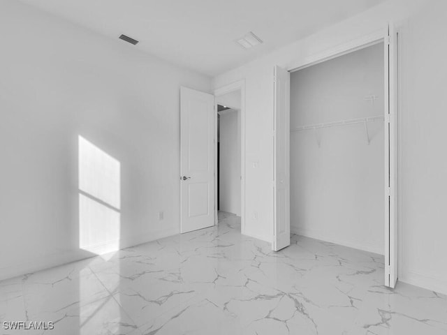 unfurnished bedroom with a closet, baseboards, marble finish floor, and visible vents