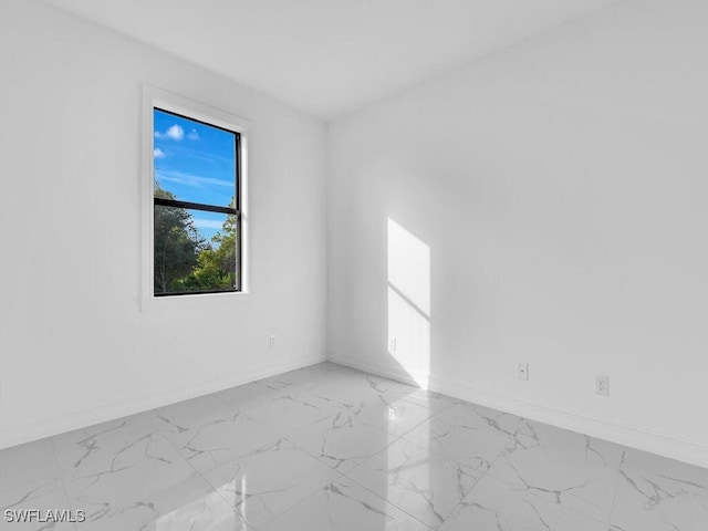 spare room with marble finish floor and baseboards