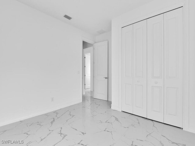 unfurnished bedroom featuring a closet, visible vents, marble finish floor, and baseboards