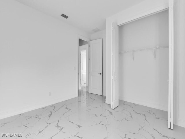 unfurnished bedroom featuring a closet, visible vents, marble finish floor, and baseboards