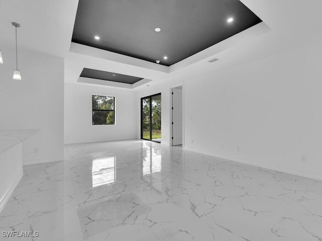 spare room featuring a raised ceiling, recessed lighting, marble finish floor, and baseboards