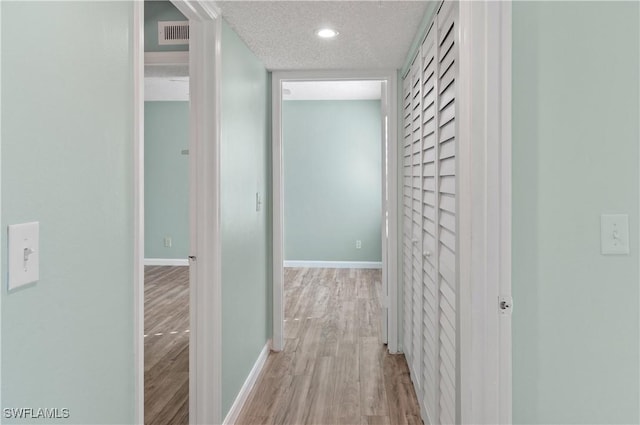 corridor featuring light hardwood / wood-style floors and a textured ceiling