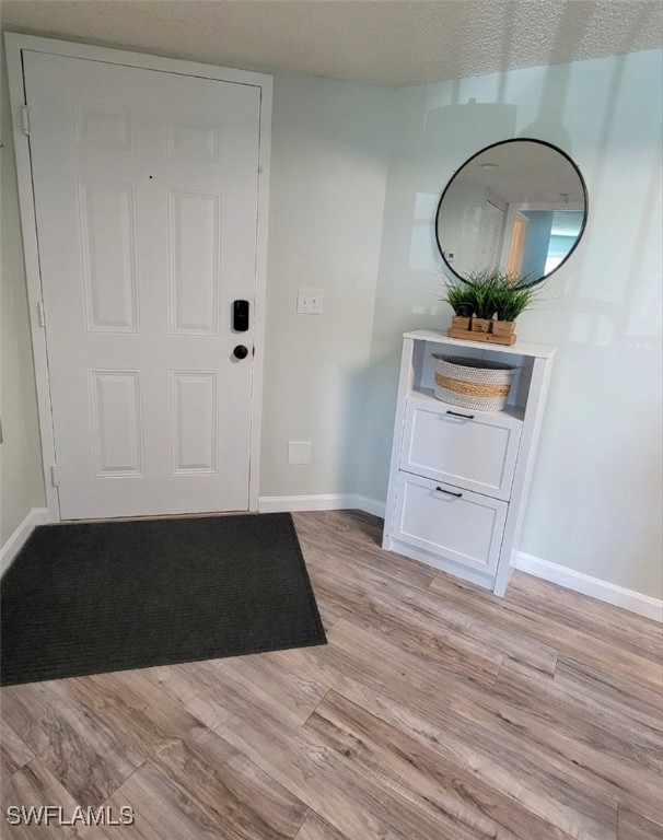 entryway with a textured ceiling and light wood-type flooring