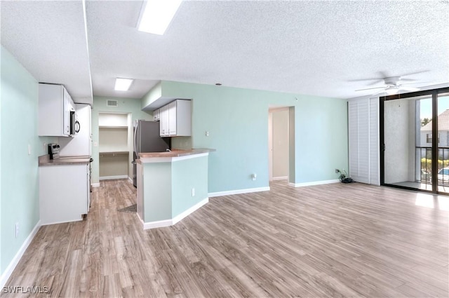 kitchen featuring white cabinetry, ceiling fan, kitchen peninsula, a textured ceiling, and light wood-type flooring