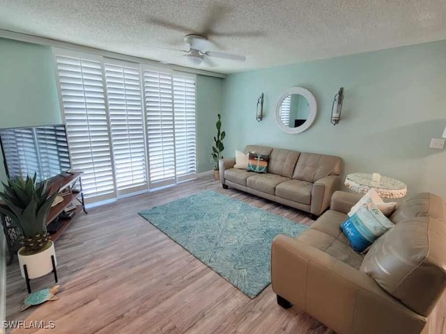 living room with ceiling fan, wood-type flooring, and a textured ceiling