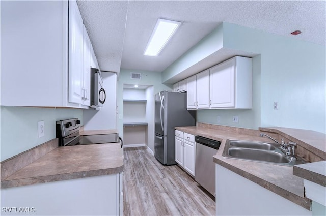 kitchen featuring white cabinets, stainless steel appliances, a textured ceiling, and light wood-type flooring