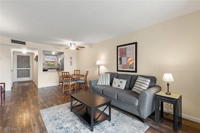 living room featuring a textured ceiling, dark hardwood / wood-style floors, and ceiling fan