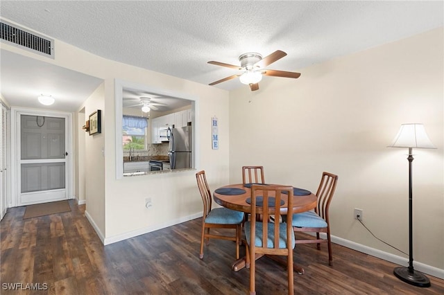 dining room featuring ceiling fan, sink, dark wood-type flooring, and a textured ceiling