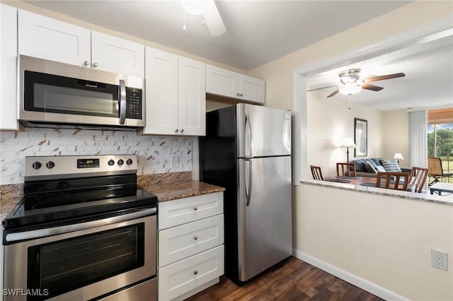 kitchen with white cabinets, decorative backsplash, dark stone countertops, appliances with stainless steel finishes, and dark hardwood / wood-style flooring