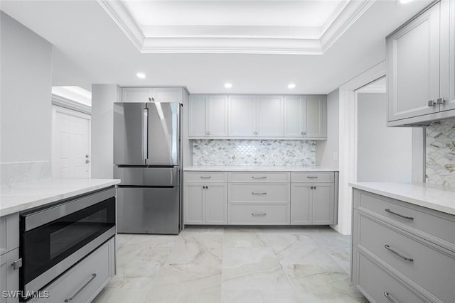 kitchen featuring gray cabinetry, backsplash, built in microwave, and stainless steel refrigerator