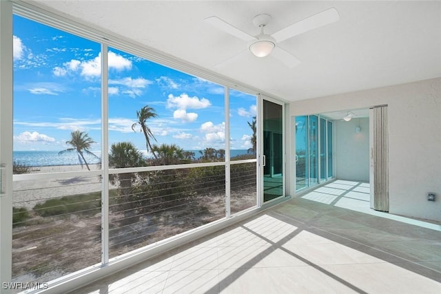 unfurnished sunroom with ceiling fan, a water view, and plenty of natural light