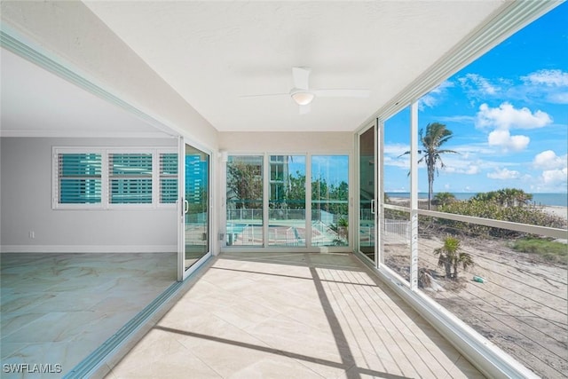 unfurnished sunroom featuring a water view and ceiling fan