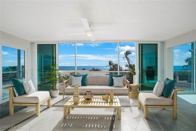 sunroom / solarium featuring ceiling fan and a water view