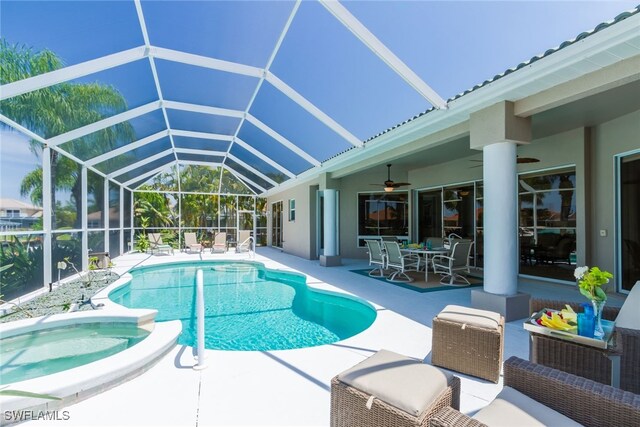 view of pool featuring ceiling fan, a patio area, an in ground hot tub, and glass enclosure