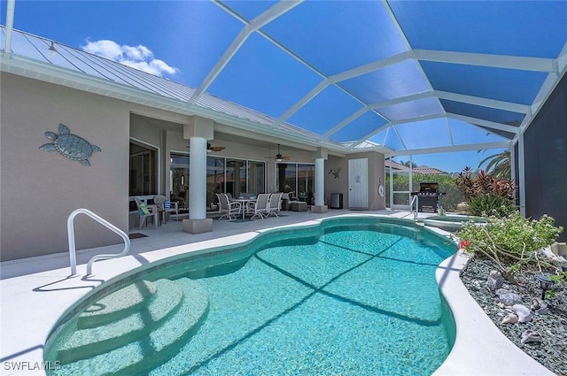 view of swimming pool with glass enclosure, ceiling fan, and a patio area