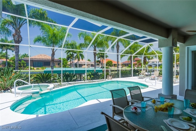 view of pool with a patio area, an in ground hot tub, and glass enclosure