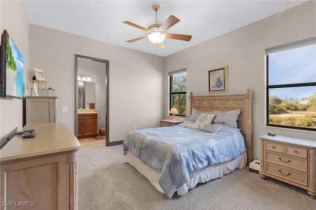 bedroom with light colored carpet, connected bathroom, and ceiling fan