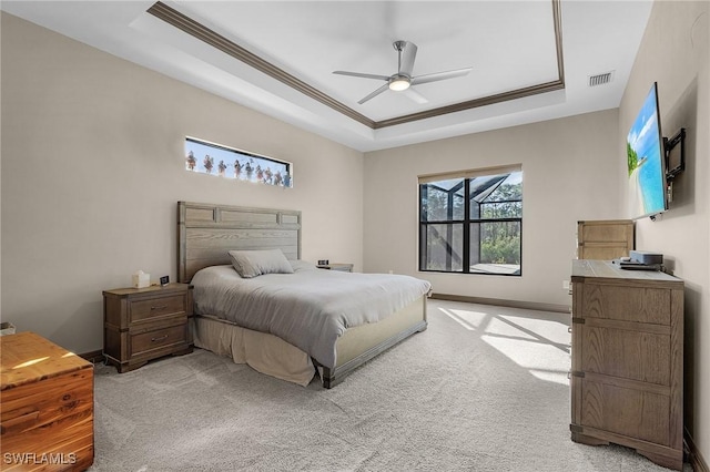 bedroom featuring ceiling fan, light carpet, and a tray ceiling