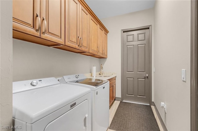 clothes washing area featuring cabinets, sink, and independent washer and dryer