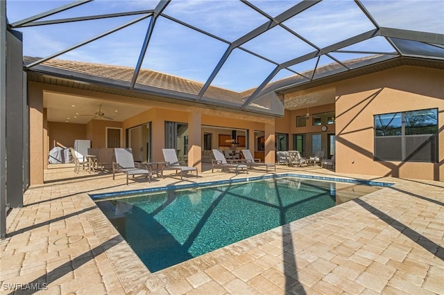 rear view of house with glass enclosure, a patio area, and ceiling fan