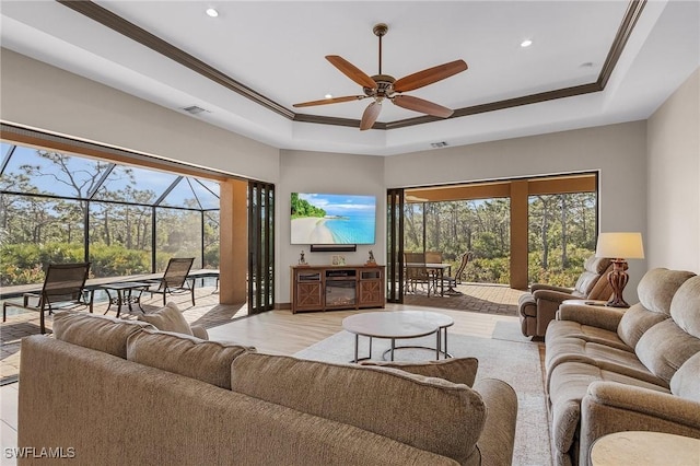 living room featuring ceiling fan, a raised ceiling, and ornamental molding