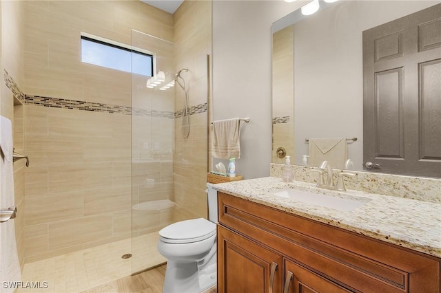 bathroom with tiled shower, toilet, and vanity