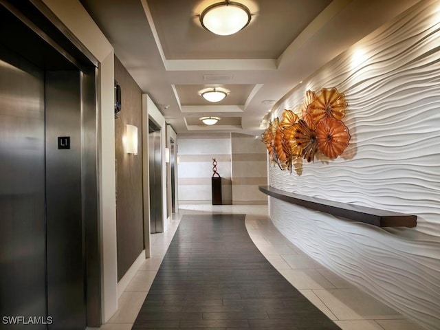 hall featuring elevator, a raised ceiling, and light hardwood / wood-style flooring