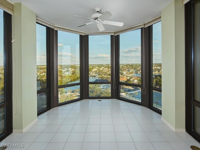 unfurnished sunroom featuring a water view and ceiling fan