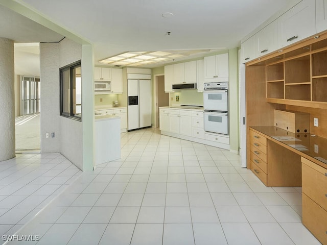 kitchen featuring light tile patterned flooring, built in appliances, and white cabinets