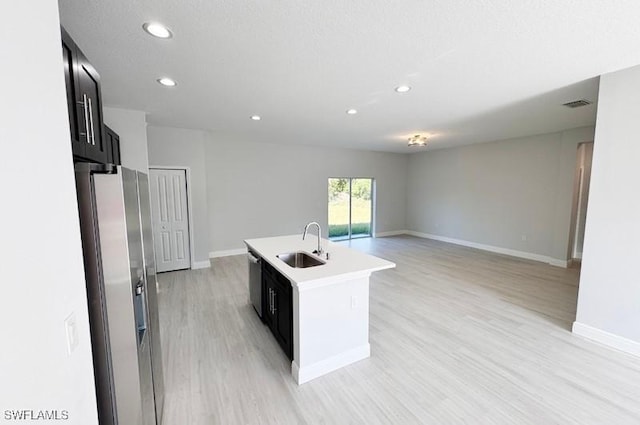 kitchen with a center island with sink, sink, light hardwood / wood-style flooring, a textured ceiling, and stainless steel appliances