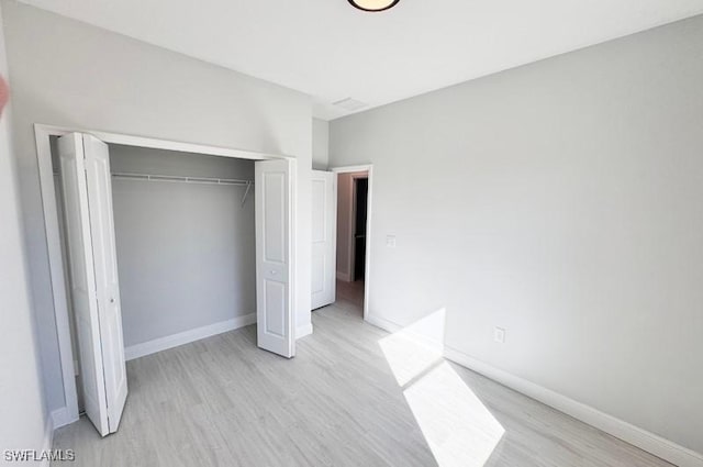 unfurnished bedroom featuring light hardwood / wood-style flooring and a closet