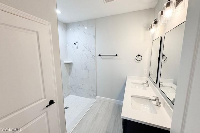 bathroom with a tile shower, hardwood / wood-style floors, and vanity