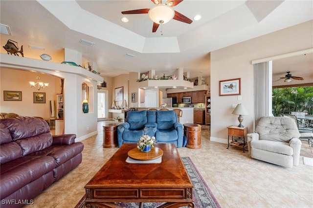 tiled living room with a tray ceiling and ceiling fan with notable chandelier