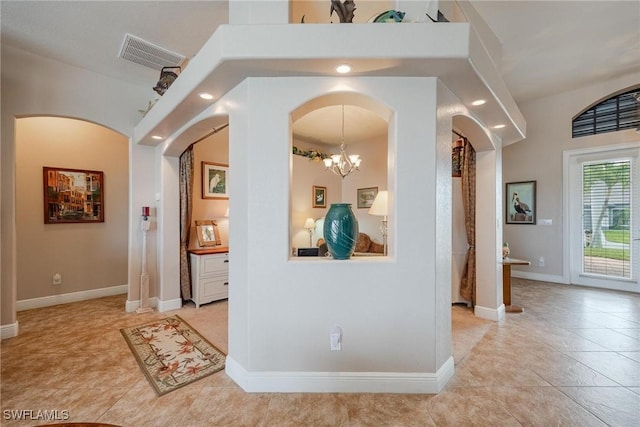 hallway with light tile patterned floors and an inviting chandelier