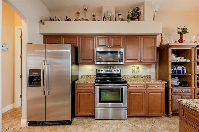 kitchen with light stone countertops, stainless steel appliances, and light tile patterned floors