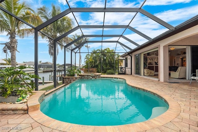 view of pool with glass enclosure, a patio area, a water view, and an in ground hot tub