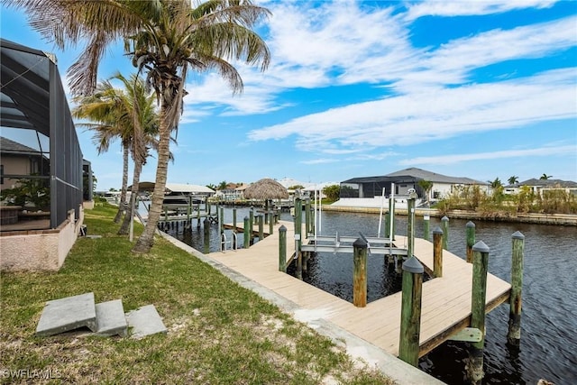 dock area with glass enclosure, a water view, and a yard