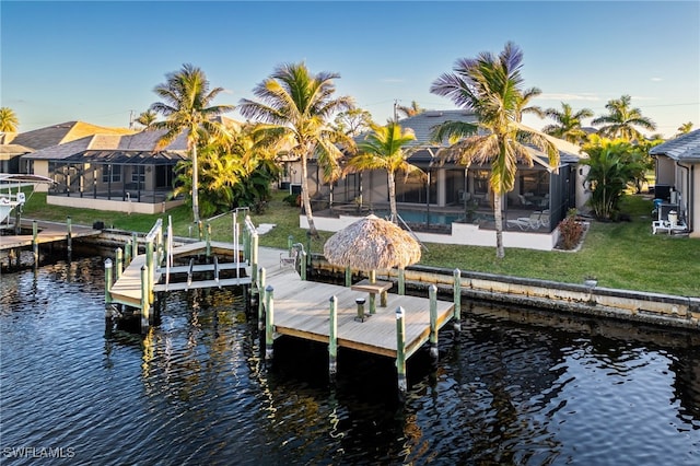 dock area featuring a lawn, glass enclosure, and a water view