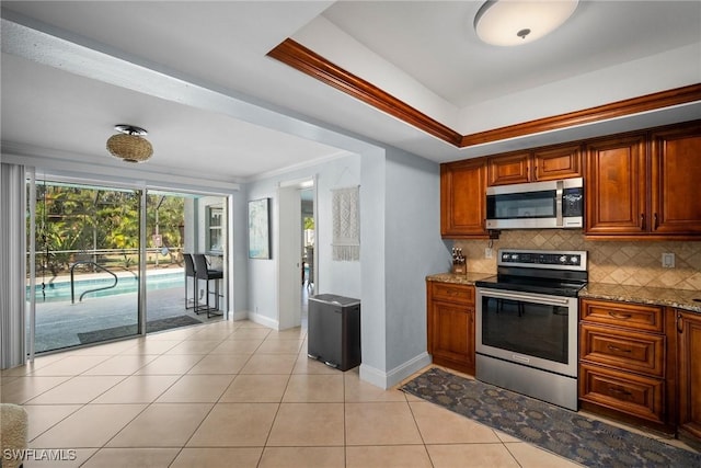 kitchen with light stone countertops, tasteful backsplash, ornamental molding, stainless steel appliances, and light tile patterned flooring