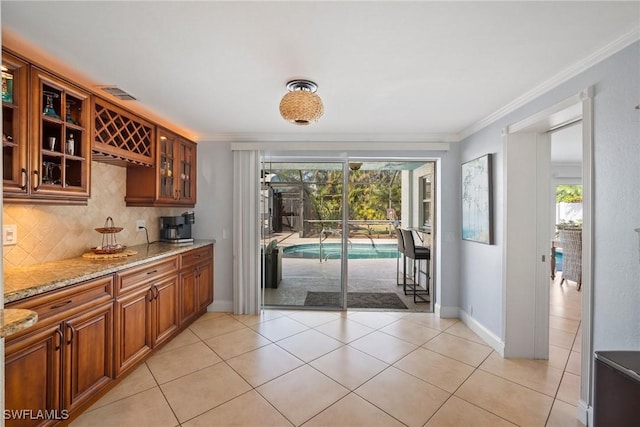 kitchen featuring decorative backsplash, crown molding, light tile patterned floors, and light stone counters