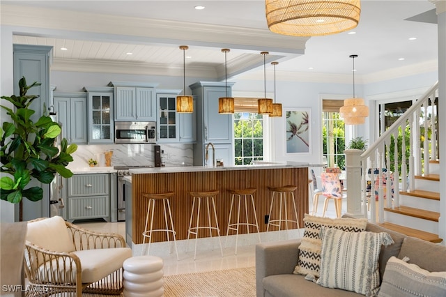 kitchen featuring pendant lighting, decorative backsplash, a kitchen island with sink, and appliances with stainless steel finishes