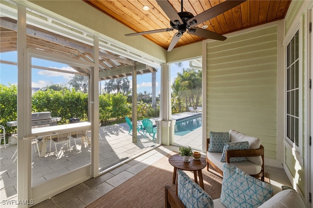 unfurnished sunroom featuring ceiling fan, a healthy amount of sunlight, and wooden ceiling