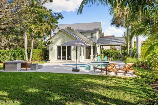 rear view of house with a lawn, a swimming pool with hot tub, and a patio